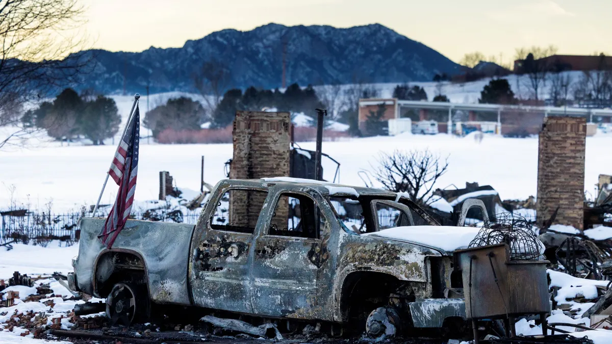 An American flag is shown affixed to a burned truck