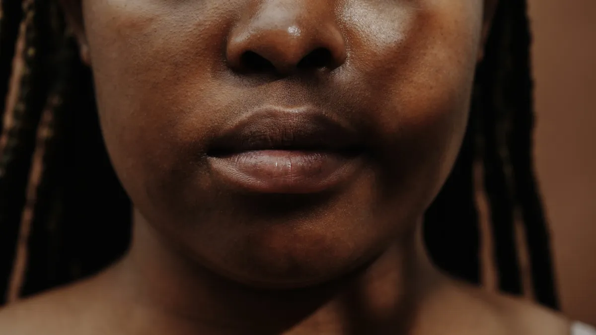 A close-up of a semi-faceless Black person with braids