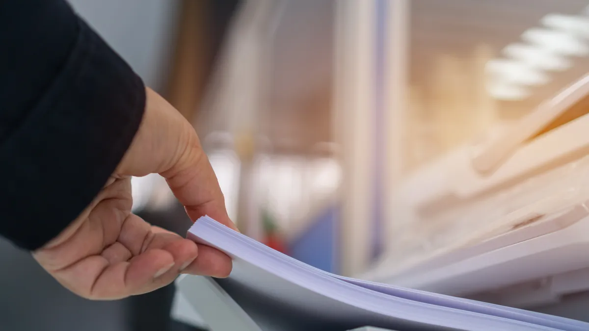 an office employee adding paper to a printer