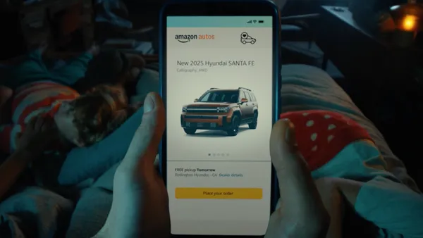 A person holds a smartphone in a dimly lit room showing Amazon Auto checkout screen and "place your order" button.