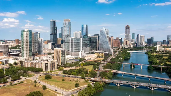 A skyline shot of a city during the day with a river in the foreground.