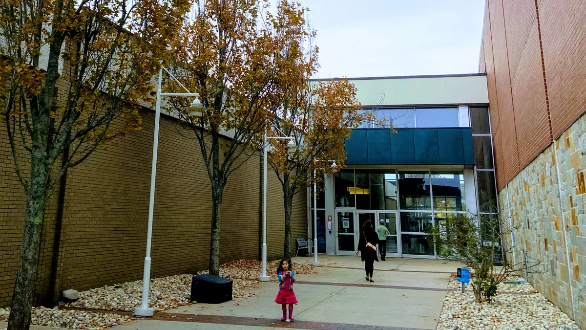 A child in front of an entrance to a shopping center.