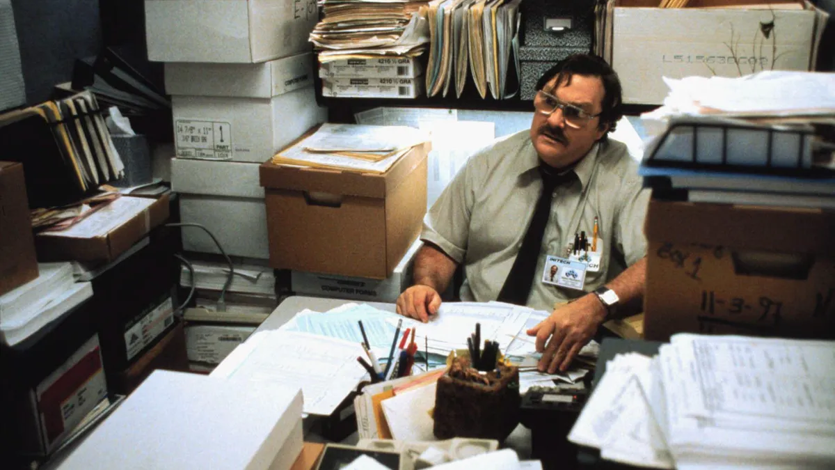 A still from the movie "Office Space" with Milton sitting at his desk.