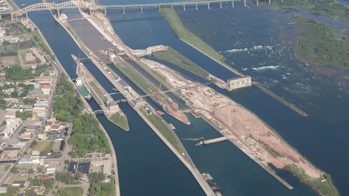 Aerial image shows lock under construction amid blue water.