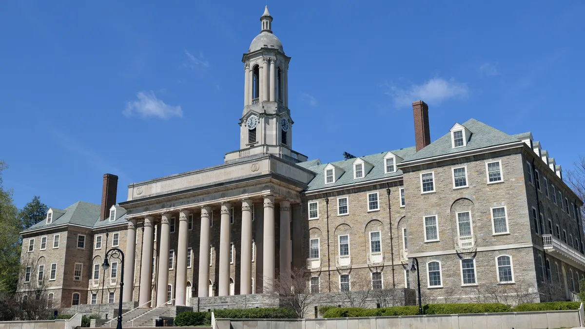 An old grey academic building with a bell tower.