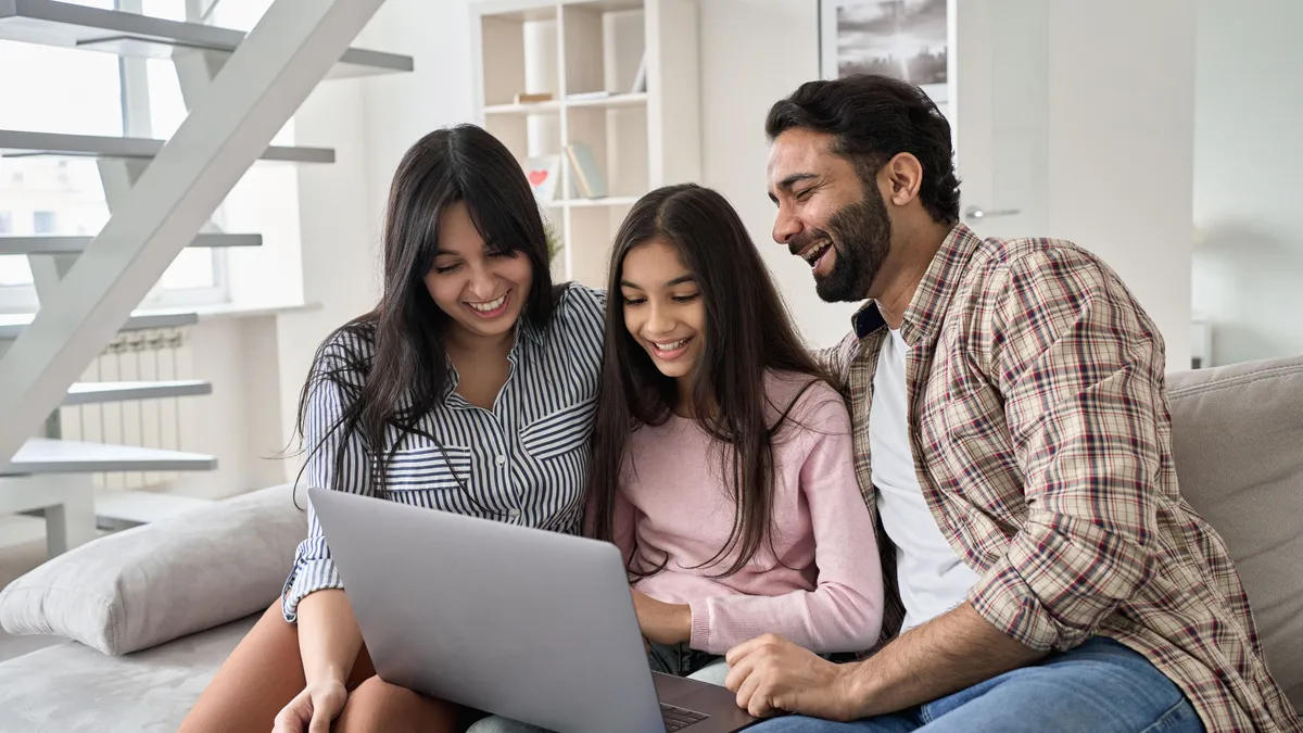 family sitting on couch looking at laptop