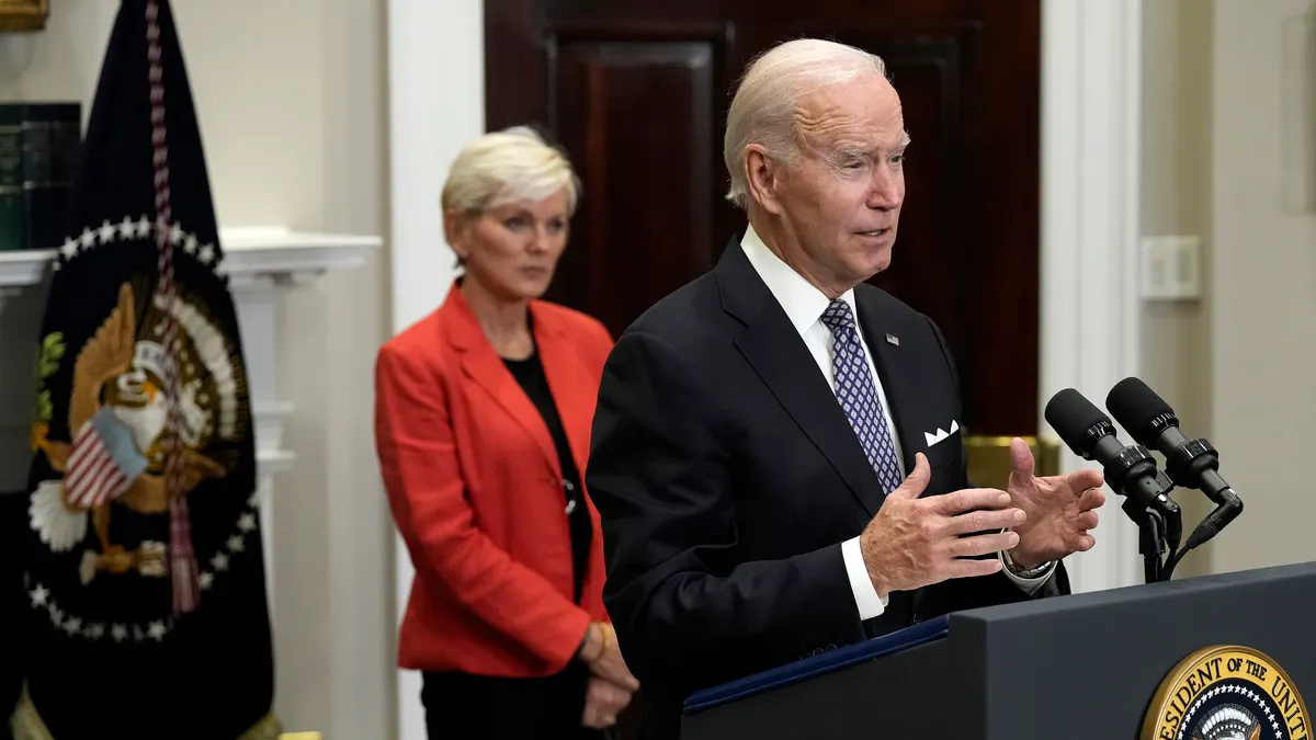 U.S. President Joe Biden speaks at a podium, with Energy Secretary Jennifer Granholm in the background.