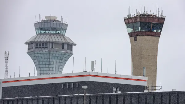Two air traffic control towers loom over an airport building
