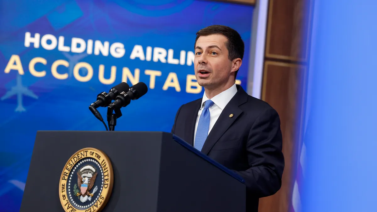 Transportation Secretary Pete Buttigieg speaks in front of a White House podium.