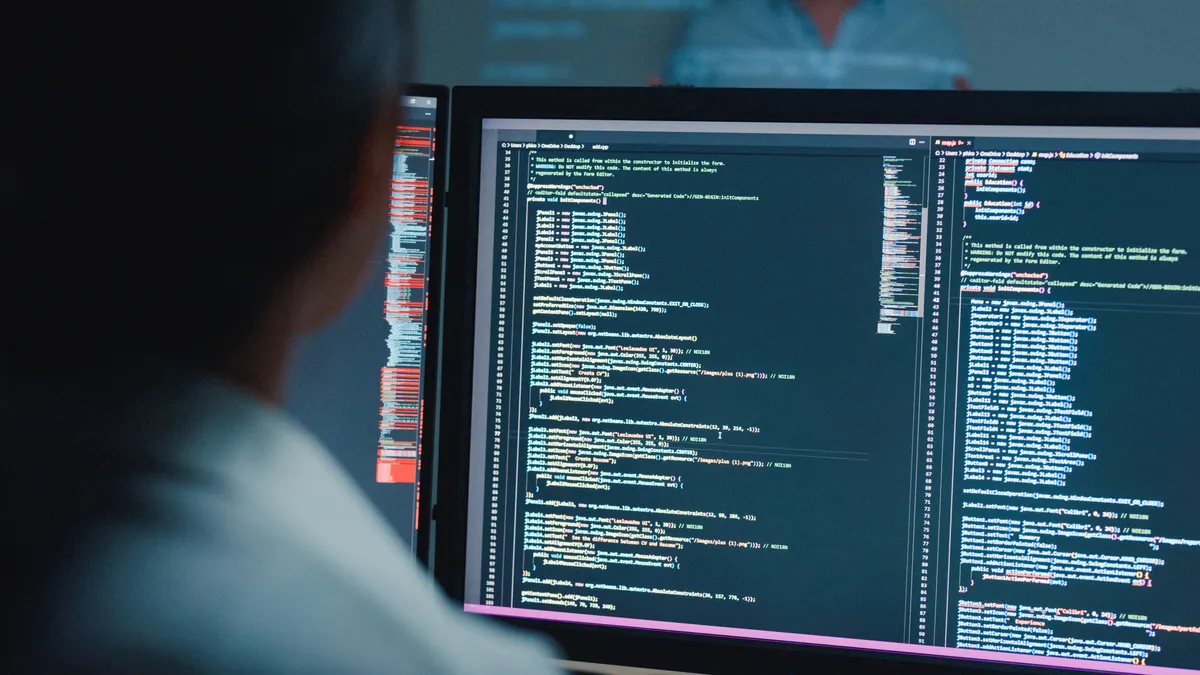 A tech worker eviews code on a computer screen