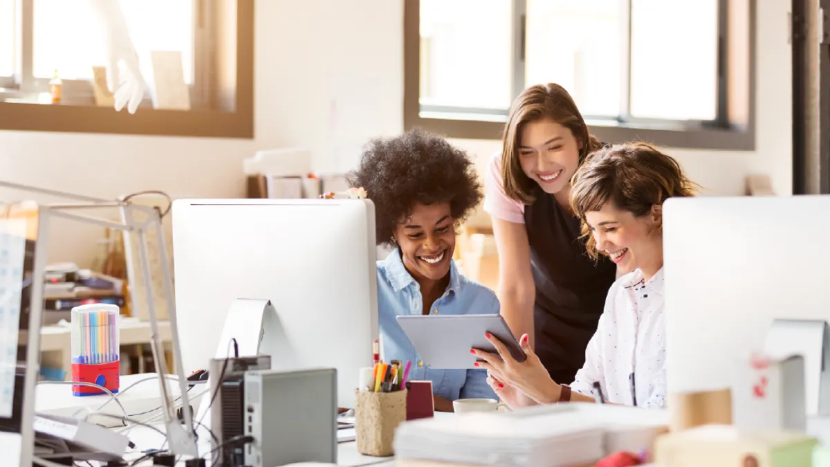 Happy businesswomen using digital tablet in office