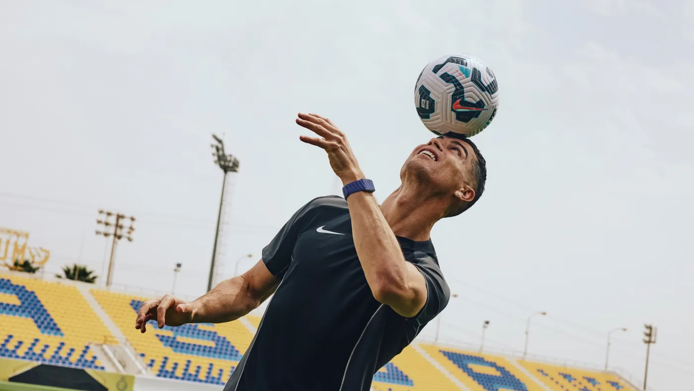 A person hits a soccer ball with their head while wearing a wristband.