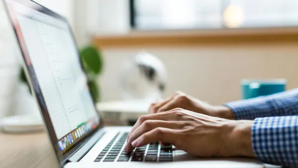 Close-up of hands typing on a laptop computer.