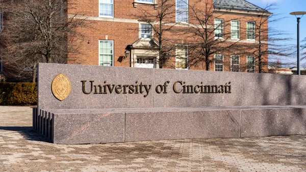 A brown stone sign that is low to the ground that shows the University of Cincinnati.