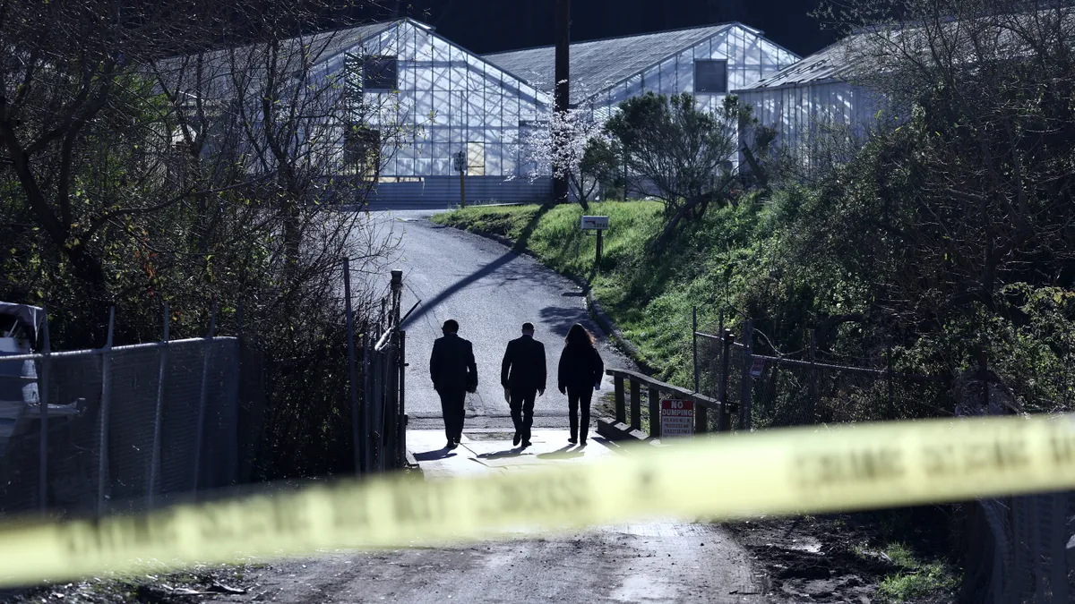 Three agents arrive at a farm at night, with yellow police tape in the foreground.