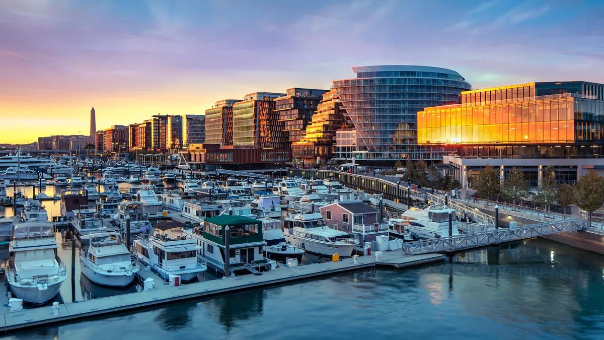 A row of glass high-rises on the right and boats docked on the left.