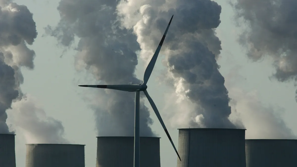 A lone wind turbine spins as exhaust plumes from cooling towers at the Jaenschwalde lignite coal-fired power station, which is owned by Vatenfall, April 12, 2007 at Jaenschwalde, Germany.