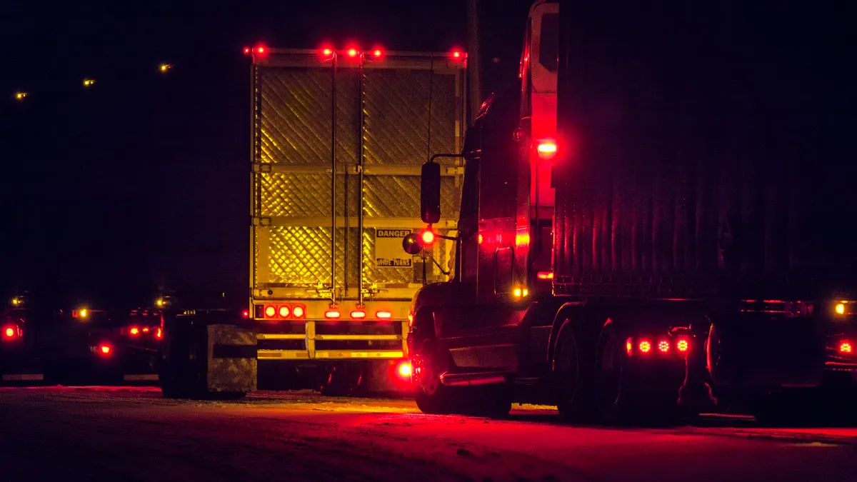 Trucks on a snowy road in New York state at night.