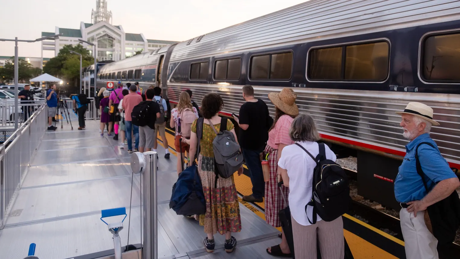 People on train station platform with a silver and blue Amtrak train.