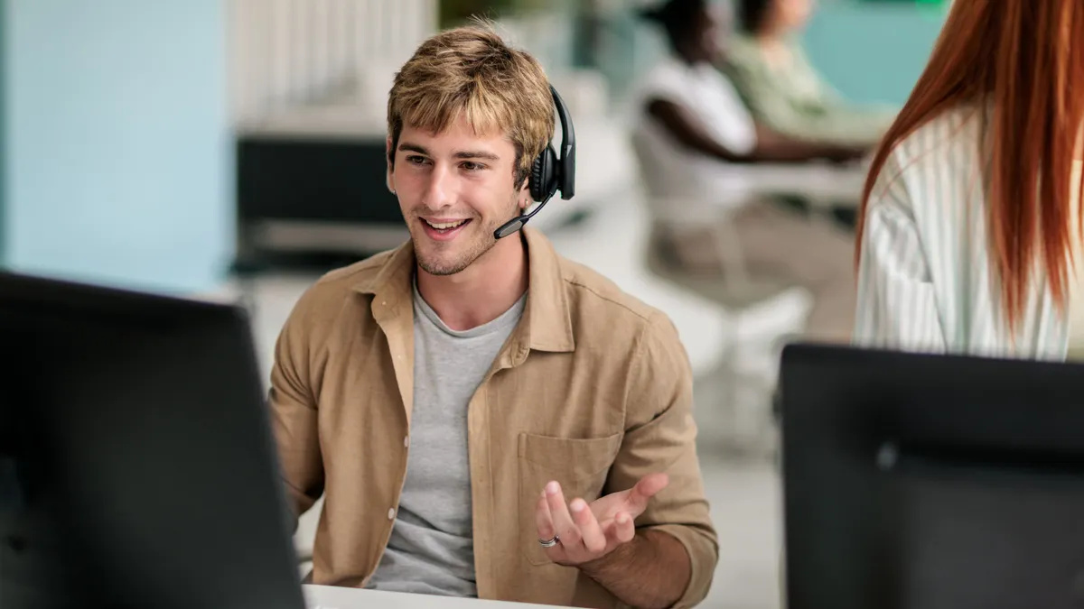 An employee with a headset is sitting in front of two monitors