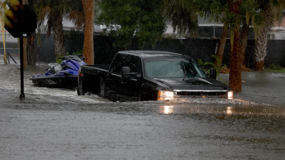 A pickup truck attempts to drive through flooded streets.