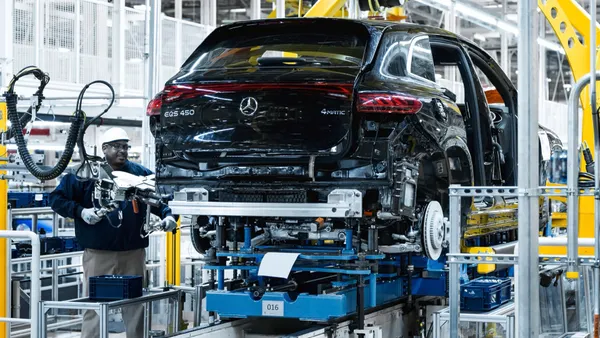 A worker helps assemble a Mercedes-Benz EQS SUV.