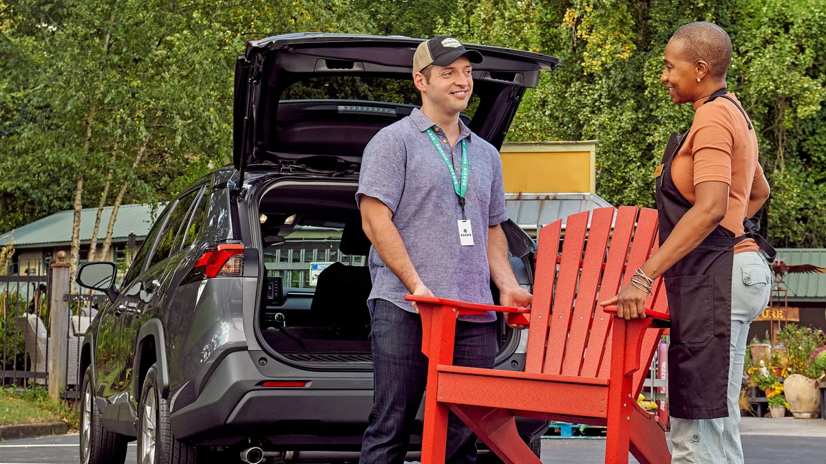 A Roadie delivery driver receives help in handling a chair.