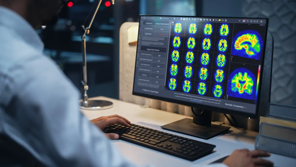 A physician looks at computer screens that show brain imaging.