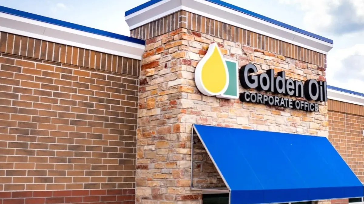 A photo of a brick building with a blue awning. A sign over the awning says "Golden Oil Corporate Office."