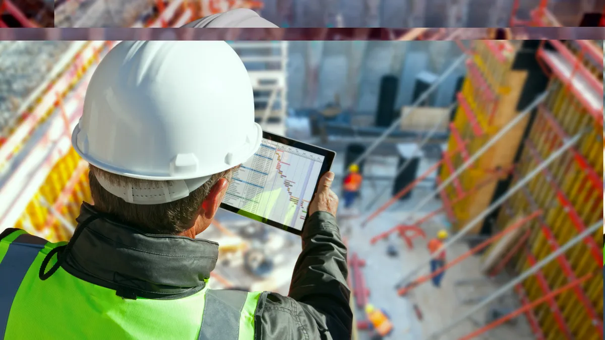 Civil engineer or architect with hardhat on construction site checking schedule on tablet