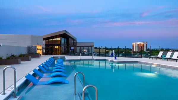 Rooftop pool at an apartment building with a a high-rise and trees in the background.