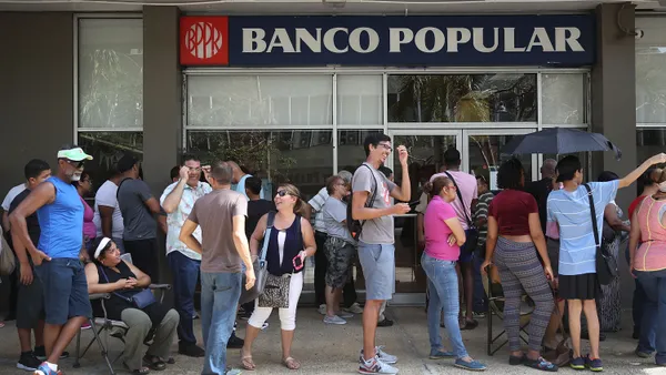 people stand in line outside of banco popular in puerto rico.