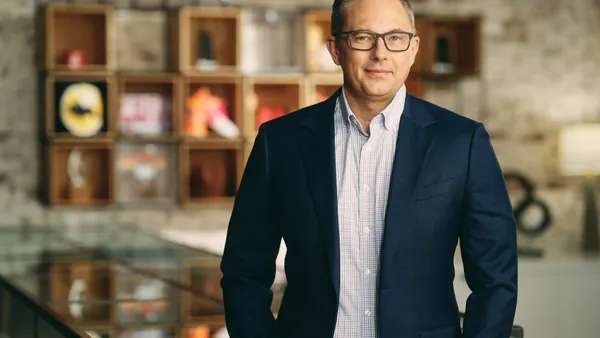 A smiling white man in a blue suit with no tie.