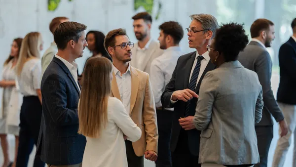 Professionals gathered, engaging in conversations and exchanging ideas at a corporate conference or seminar.