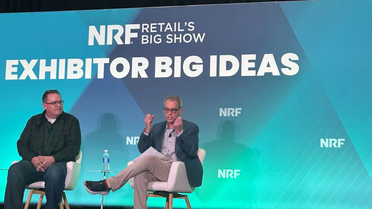Panel with two white men on stage and a blue background that reads 'NRF'