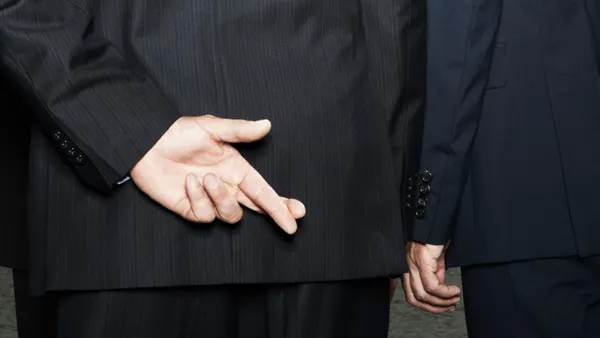 Businessman secretly crossing fingers