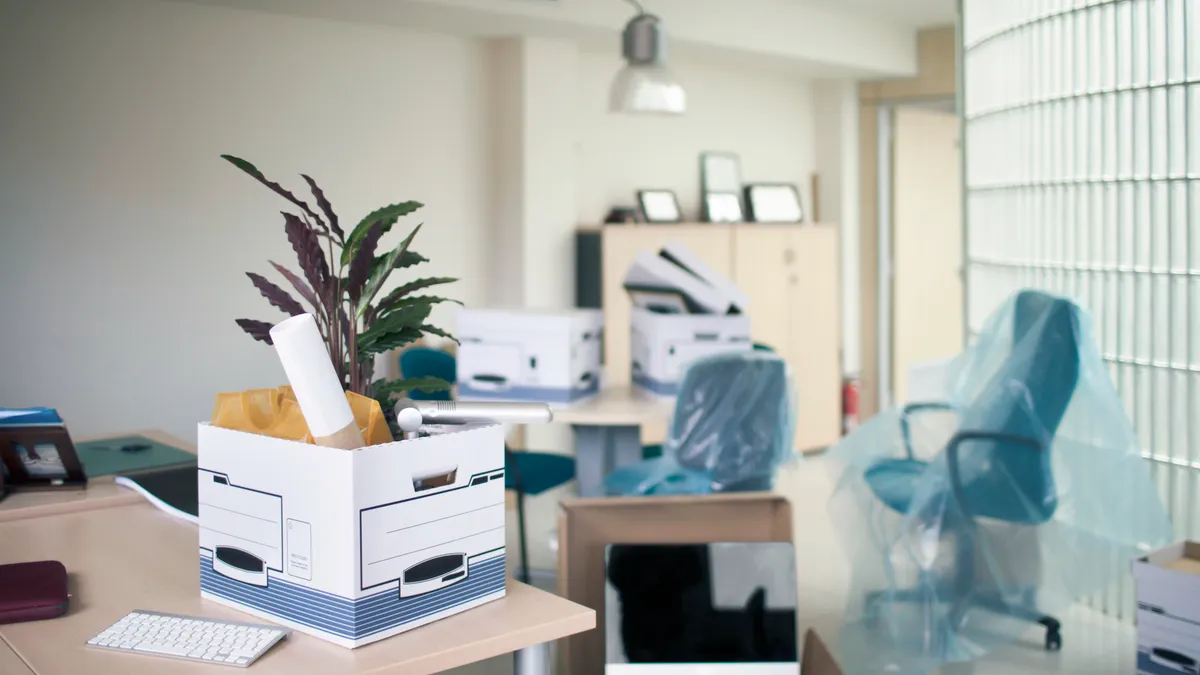 Belongings in box on desk. Interior of new office. Furniture is in modern workplace.