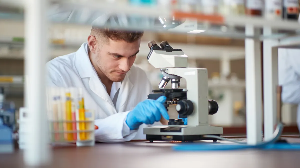 A young man looks through a microscope in a science lab