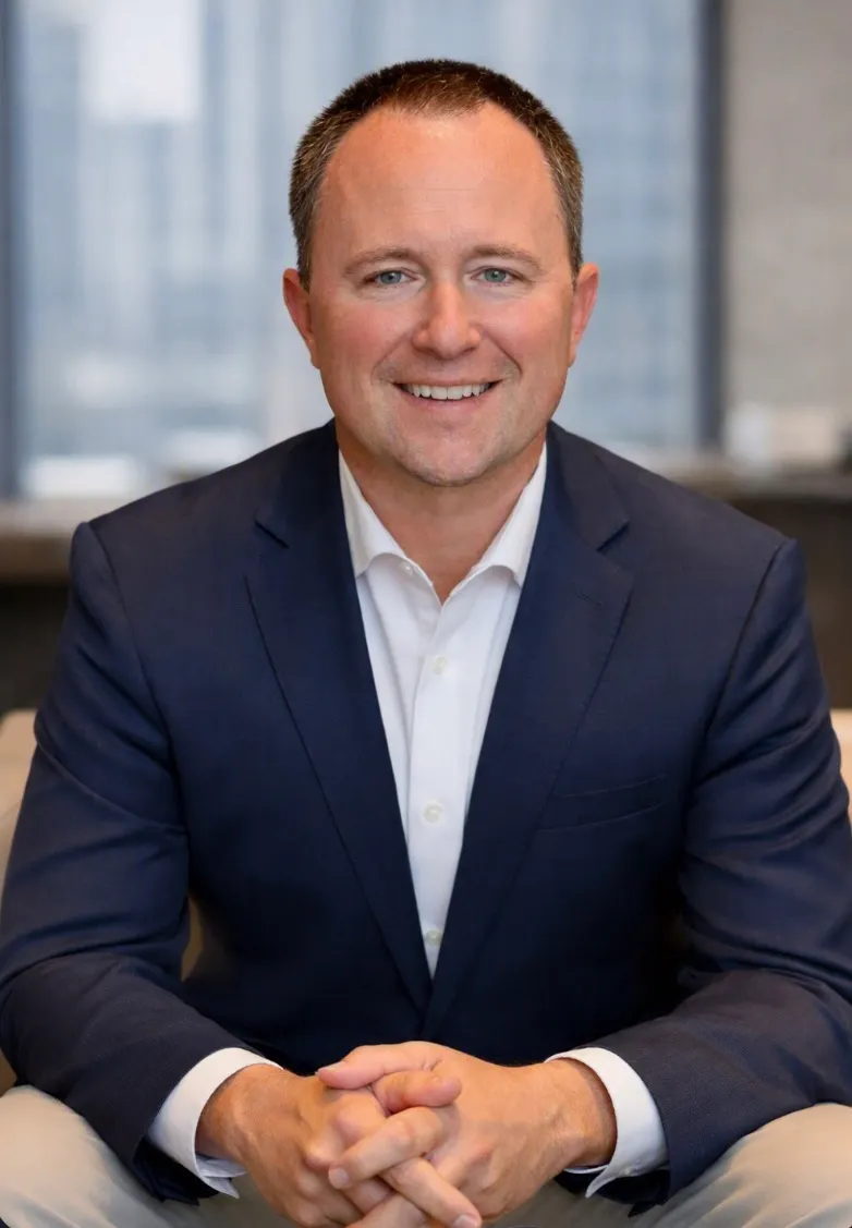 A person wearing a suit jacket smiles for the camera.