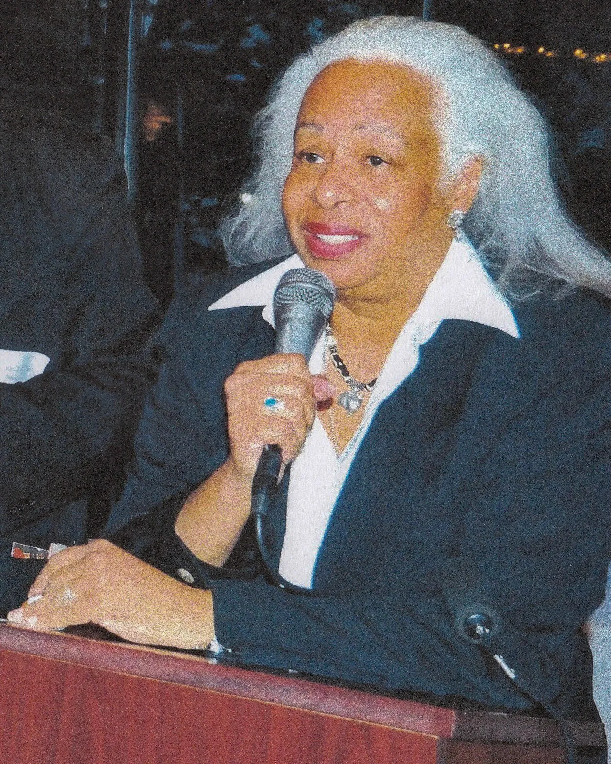 A person stands at a podium speaking into a microphone.