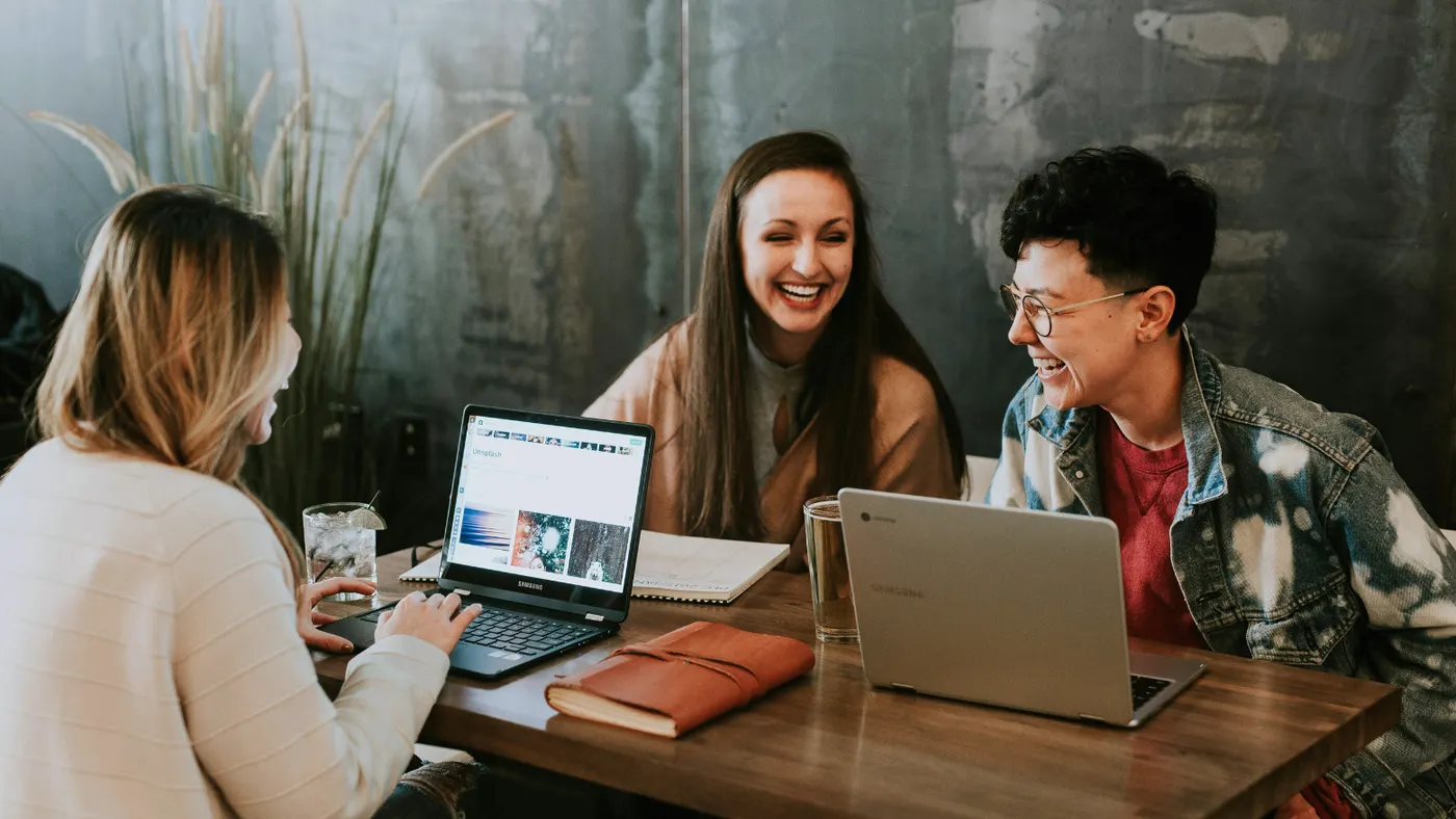 three people sitting around a table laughing