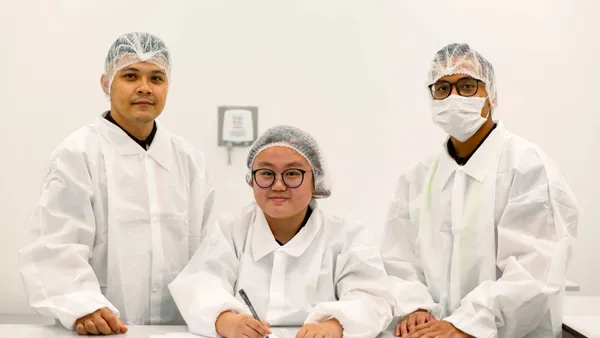 3 people wearing lab coats and hairnets