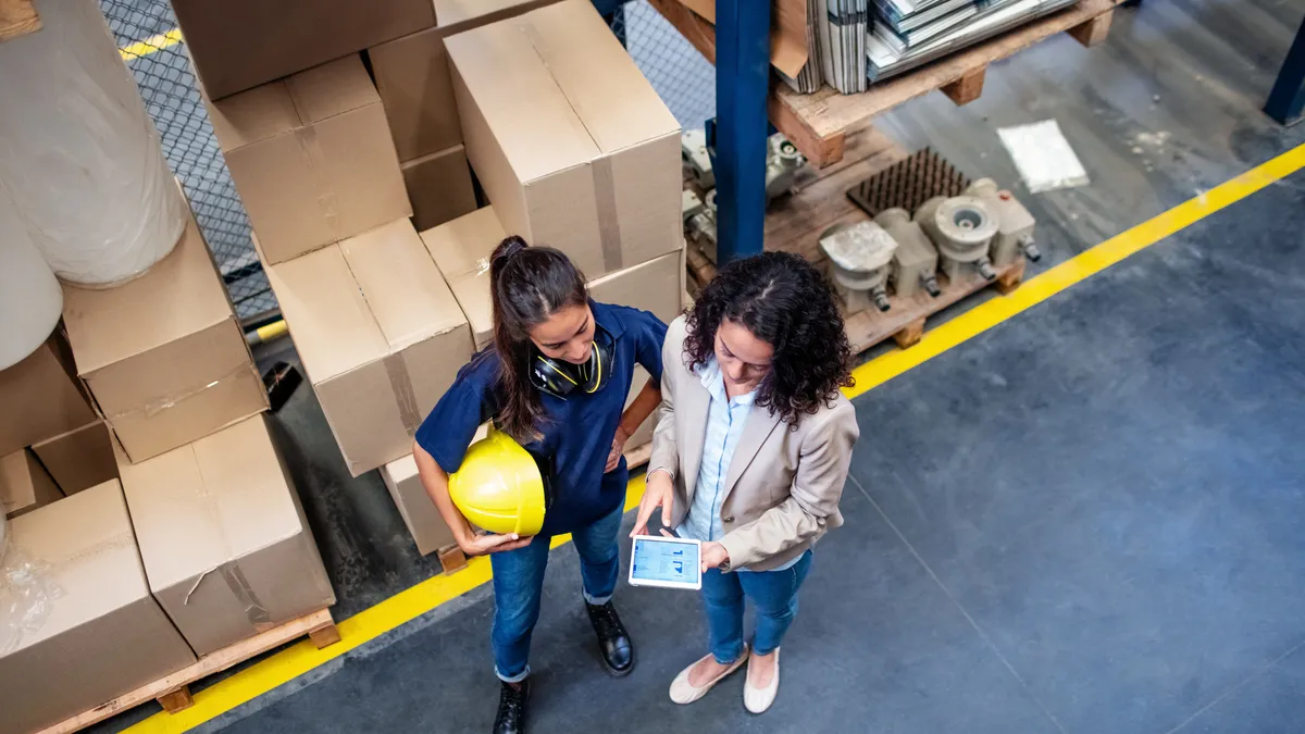 Executive and warehouse employee looking at a tablet.