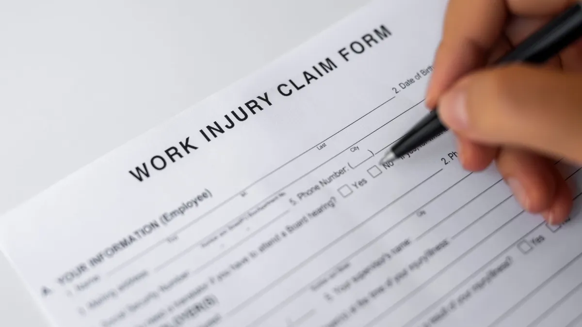 A person fills out a workers' compensation claim forms.