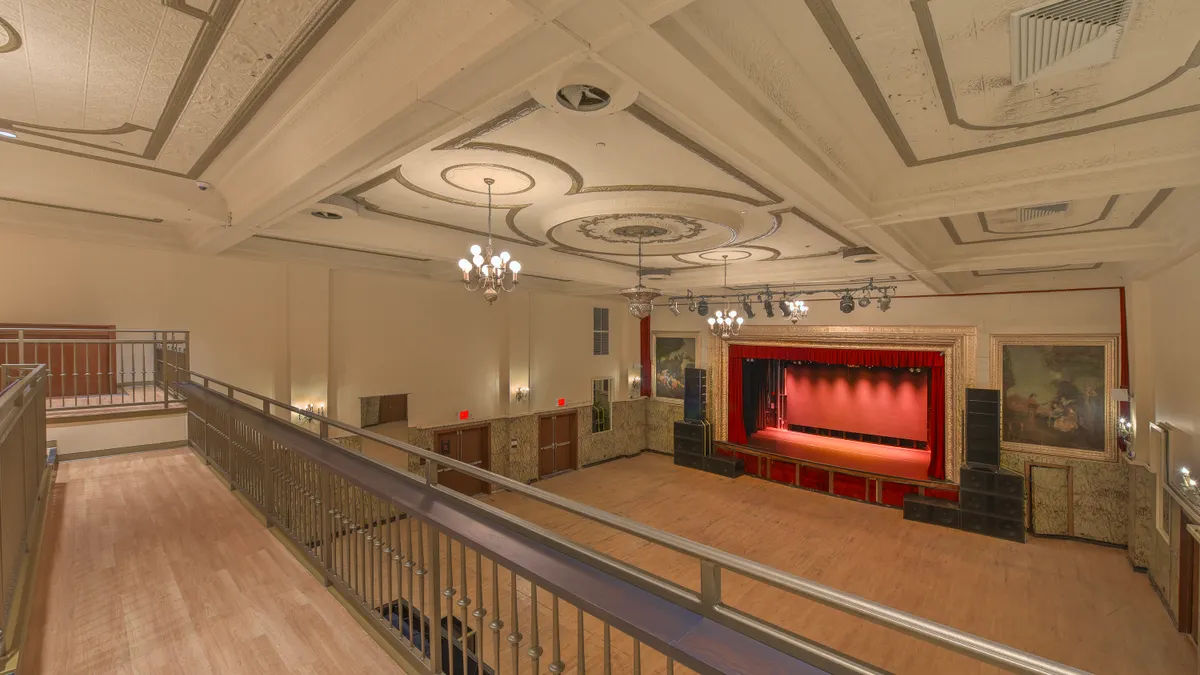 An empty theater is shown in the photo with a stage in the background.