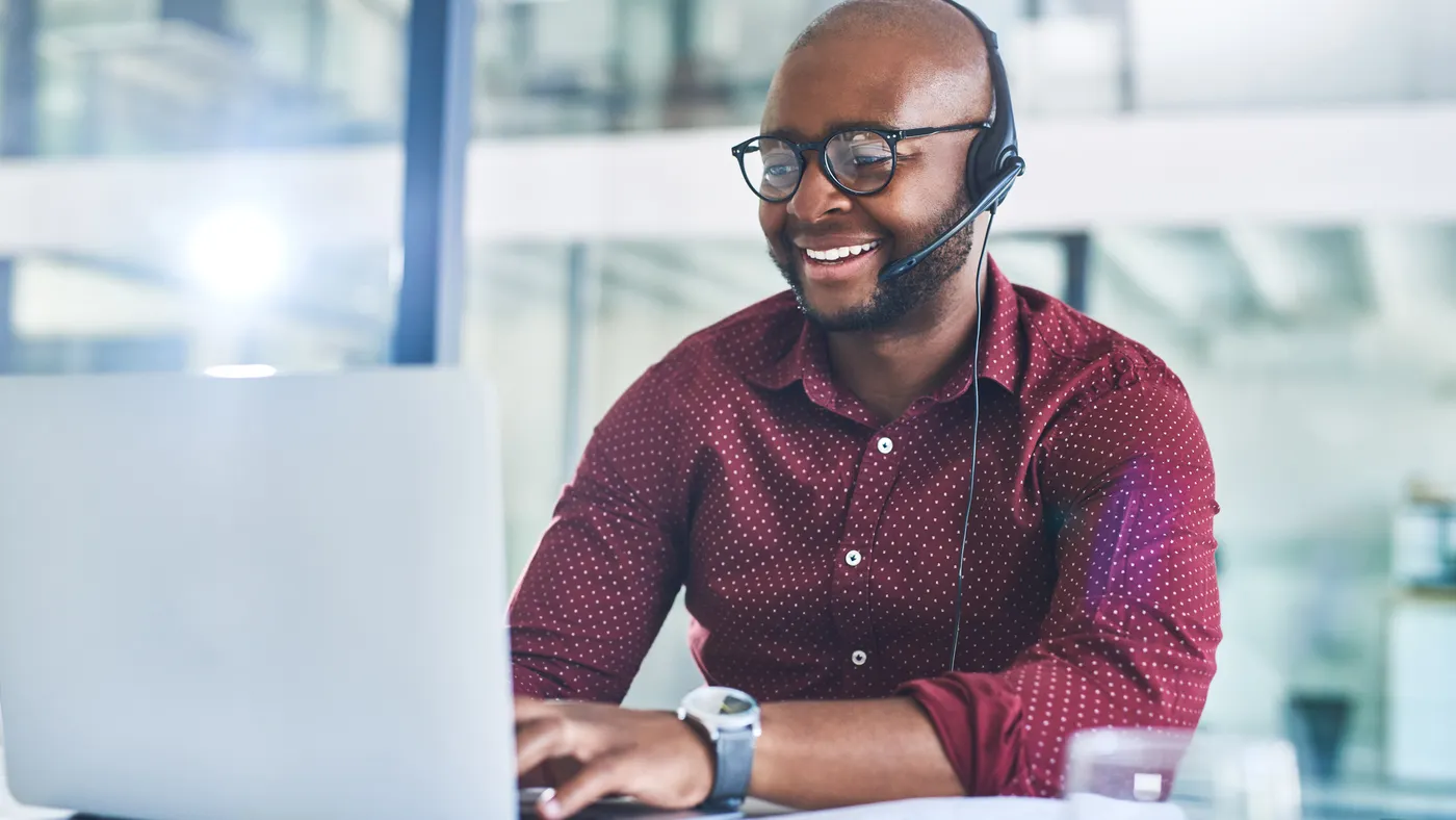 Cropped shot of a person working on a laptop with a headset