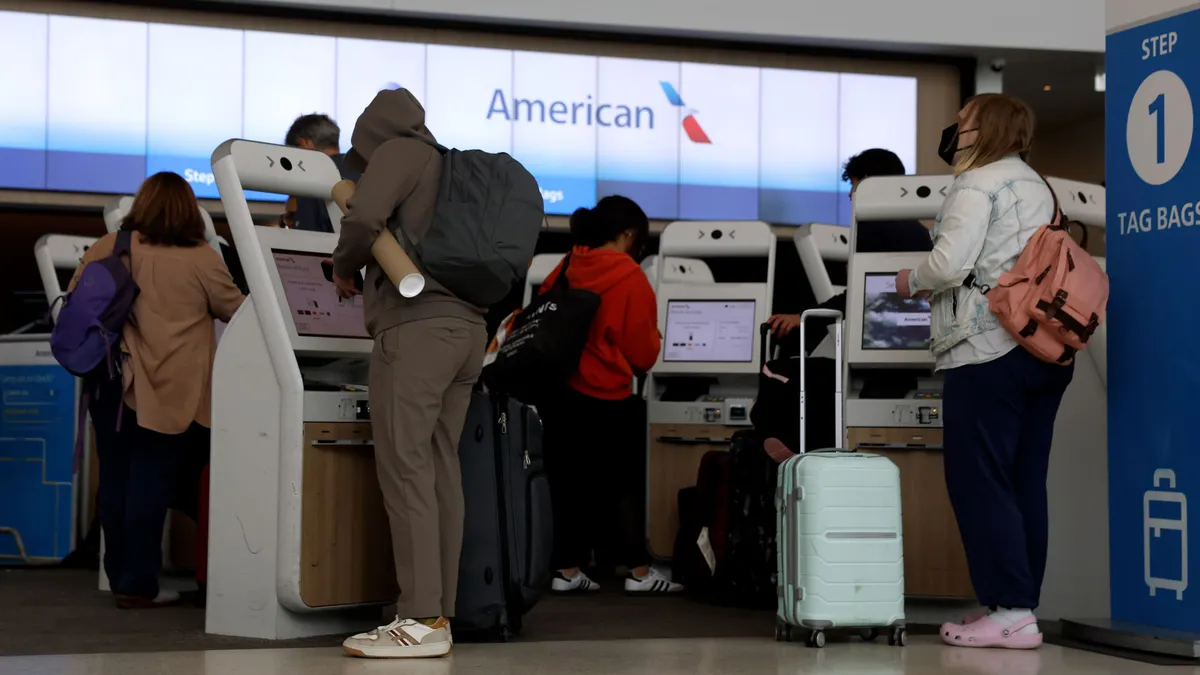 People check in at kiosks at an airport.