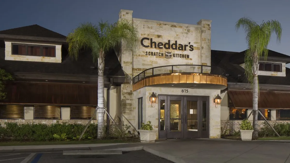 An evening photo of a beige brick building with brown letters that say "Cheddar's Scratch Kitchen."