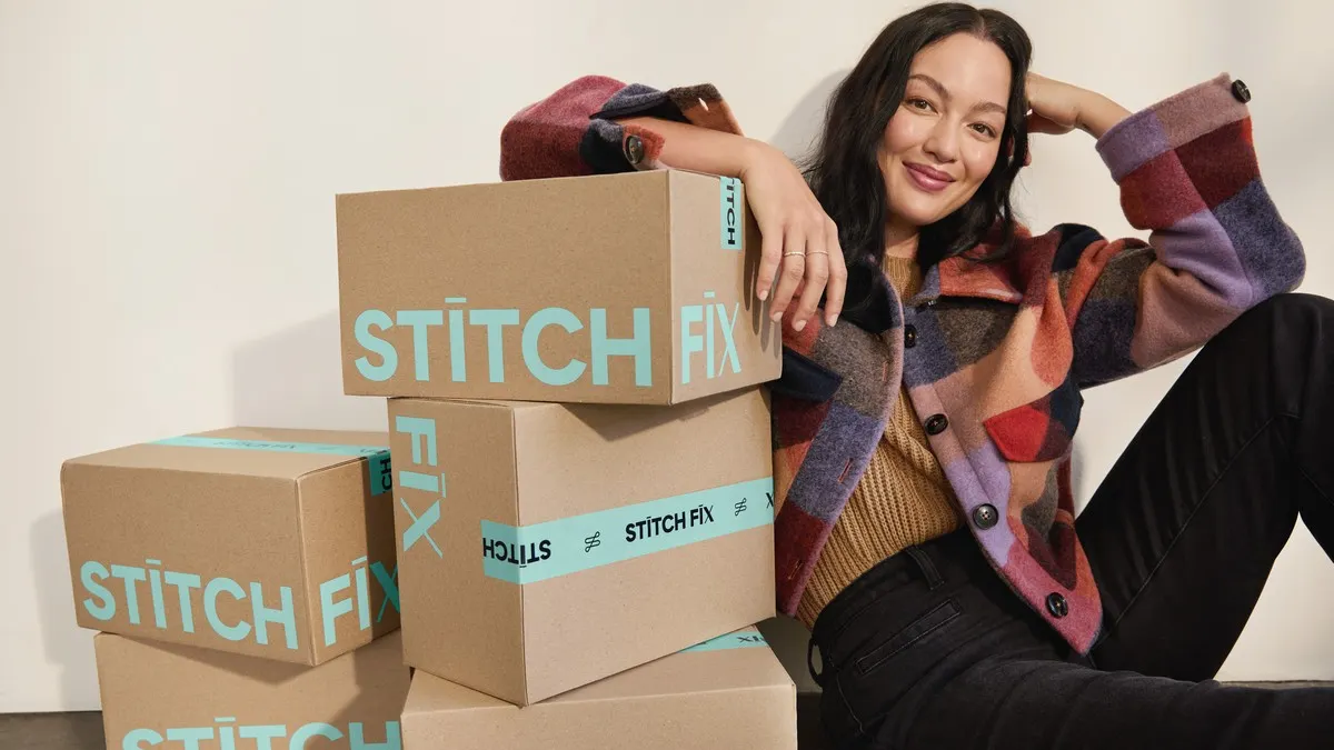 A woman sits in front of Stitch Fix boxes.
