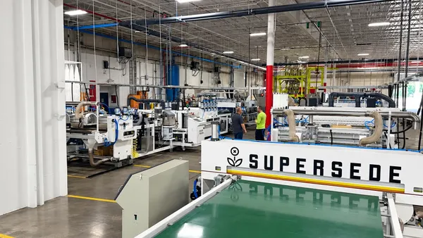 Workers stand in Supersede's Indiana manufacturing facility amid rows of machinery